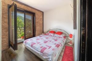 a bedroom with a bed with red pillows and a window at Apartments Vidik in Ivanjica