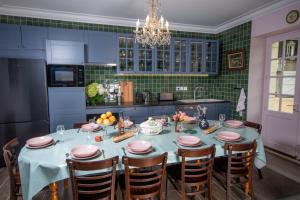 une cuisine avec une table avec des armoires bleues et du carrelage vert dans l'établissement maison d'hôtes ed.André 10 personnes, à Azay-sur-Cher