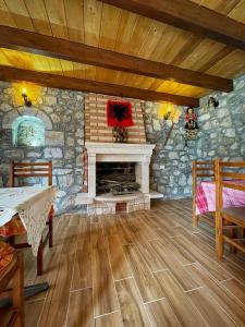 a living room with a stone fireplace and wooden floors at Guest House Rrashkadoli in Theth