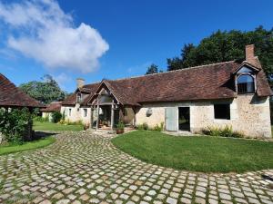 une ancienne maison en pierre avec une allée pavée dans l'établissement Cottage authentique avec piscine, à Prunay-Cassereau