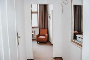a corridor of a hotel room with a chair and a mirror at B&B Hotel Praha in Nový Jičín