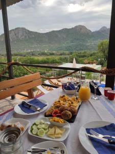 uma mesa com pratos de comida com montanhas ao fundo em Apartments Kingfisher em Virpazar