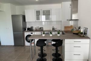a kitchen with white cabinets and a counter with stools at New appartement with 2 bedrooms in a new building in Cagnes-sur-Mer