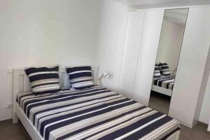 a bedroom with a bed with striped pillows and a mirror at New appartement with 2 bedrooms in a new building in Cagnes-sur-Mer