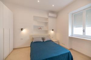 a bedroom with a blue bed and a window at Marina Grande Holiday Apartment in Capri in Capri