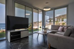 Achlia Beach Villa 2 في Achlia: غرفة معيشة مع تلفزيون بشاشة مسطحة وأريكة