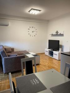 a living room with a couch and a clock on the wall at Royal Residence Apartmani in Pančevo