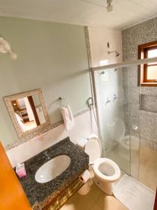 a bathroom with a sink and a toilet and a shower at Rosamar Suites in Praia do Rosa