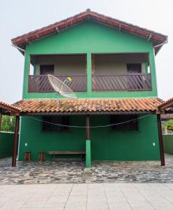 a green building with a bench in front of it at Casa de Praia - Ilha Comprida in Ilha Comprida