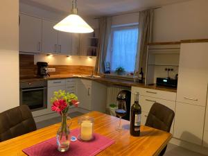 una cocina con una mesa de madera con botellas de vino y flores en Ferienwohnung Das Inge De Unterne en Bernau am Chiemsee