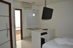 a white room with a desk with a tv on the wall at Ele e Ela Motel (Adult Only) in São Gonçalo do Amarante