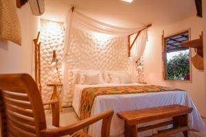 um quarto com uma cama, uma cadeira e uma janela em EcoCharme Pousada Netuno em Fernando de Noronha