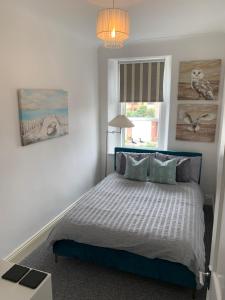a bedroom with a bed with a blue headboard and a window at On The Harbour - unrivalled views of Amble's harbour and estuary in Amble