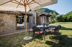 einen Tisch und Stühle unter einem Regenschirm im Hof in der Unterkunft I Casali di Villa Benveduti in Gubbio