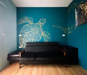 a room with a black couch and a blue wall at Little Ryukyu Hermit Crab Homestay in Xiaoliuqiu