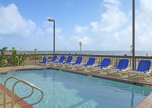 - une piscine avec des chaises bleues et la plage dans l'établissement The Breakers Resort Inn, à Virginia Beach
