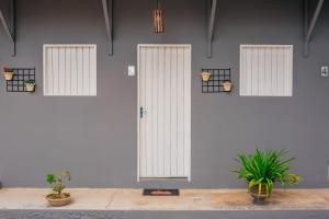a white wall with three doors and three potted plants at Pousada e Restaurante Manaím in Passa e Fica