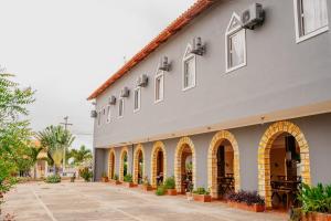 a large white building with arches and a courtyard at Pousada e Restaurante Manaím in Passa e Fica