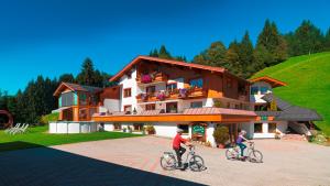 two people riding bikes in front of a building at Ferienwohnung Saalbach Fieberbrunn in Fieberbrunn