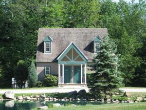una pequeña casa con un estanque delante en Spruce Hill Inn & Cottages, en Mansfield