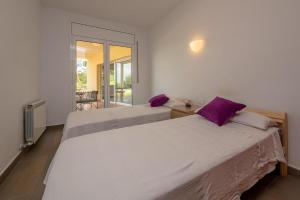 two beds in a white room with purple pillows at RB-5 RESIDENCIAL BEGUR 6 PaX in Begur