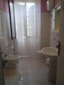 uma casa de banho com 2 lavatórios, um WC e uma janela em I Tre Leoni Affittacamere em Civitavecchia