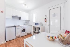 a kitchen with white cabinets and a white table at Villas New Lanzasuites in Playa Blanca
