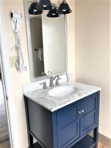 a bathroom with a sink, mirror, and soap dispenser at Westport Inn in Westport