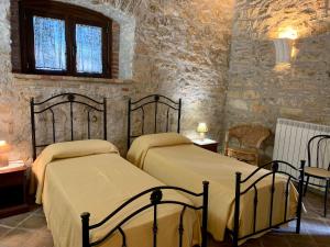 two beds in a room with stone walls at Agriturismo Sant'Agata in Piana degli Albanesi