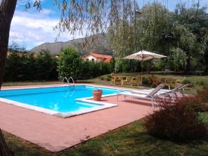 a swimming pool with an umbrella and a table and chairs at Hotel Palacio Garcia Quijano in Los Corrales de Buelna +43 photos