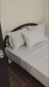 una cama con almohadas blancas encima en The Rochester Condo, en Manila