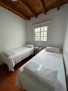 2 letti in una camera bianca con finestra di APARTAMETOS ELENA 11 a Lajares
