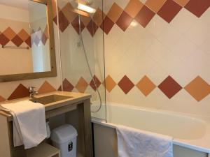 een badkamer met een wastafel en een bad bij travelski home classic - Résidence La Muzelle in Les Deux Alpes