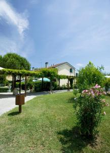 um jardim com uma pérgola e flores e uma casa em Villaggio Teodorico em Punta Marina