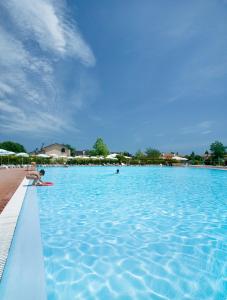 a person in a swimming pool next to a beach at Villaggio Teodorico in Punta Marina