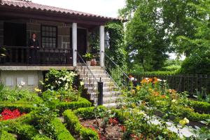 uma mulher de pé na varanda de uma casa com flores em Casa Dos Gomes em Viseu