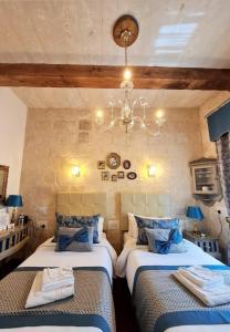 a bedroom with two beds and a chandelier at Casa Asti in Valletta