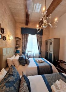 a hotel room with two beds and a chandelier at Casa Asti in Valletta
