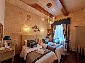 a bedroom with two beds and a stone wall at Casa Asti in Valletta