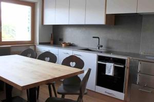 a kitchen with a wooden table and a table and chairs at Ampio appartamento di 200mq nel cuore di Antermoia in Antermoia