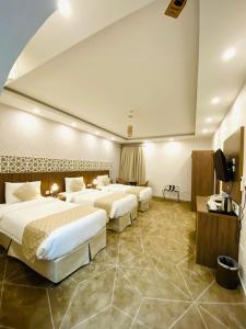 a hotel room with three beds and a television at فندق الميار , Al Mayar Hotel in Al Madinah