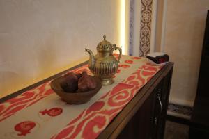 uma tigela de fruta e uma chaleira de chá numa mesa em Sugdiyon Hotel em Khujand