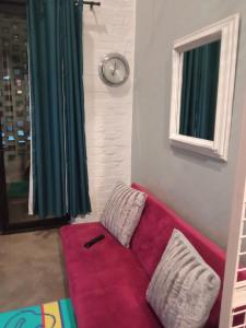een rode bank in een kamer met een klok aan de muur bij Maboneng City Building Free WiFi and Swimming pool in Johannesburg