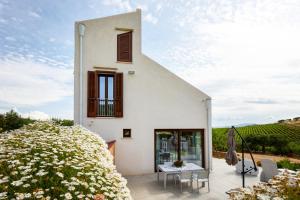 een wit huis met een patio en bloemen bij Zu Bastianu House in Alcamo