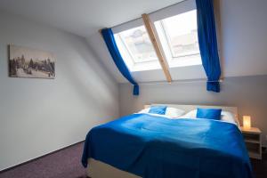 a bedroom with a bed with blue sheets and a window at Adeba Hotel in Prague
