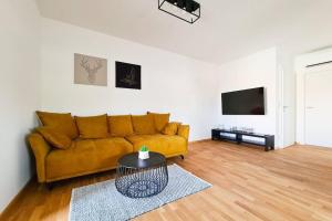 uma sala de estar com um sofá amarelo e uma televisão em Friendship Suite em Mörbisch am See