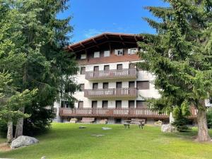 een groot gebouw met een bank in een park bij Casa Vacanze a Madonna di Campiglio in Madonna di Campiglio