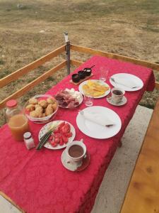 Village Cottage في زبلجك: طاولة مع قماش الطاولة الحمراء مع الطعام عليها
