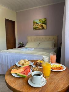 a table with breakfast foods and drinks on a bed at Pousada e Chalés Arco-Íris in Lima Duarte
