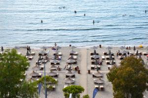 a beach with chairs and umbrellas and people in the water at Yacht Hotel in Vlorë
